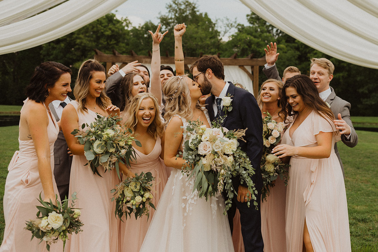 Bride and Groom Kissing with Wedding Party Cheering On