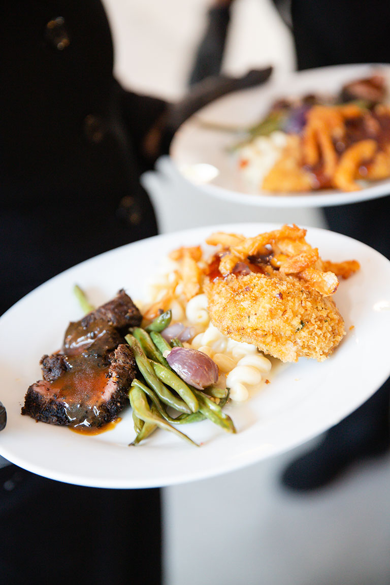 Plated dual entree of beef and chicken with green beans and truffle macaroni and cheese