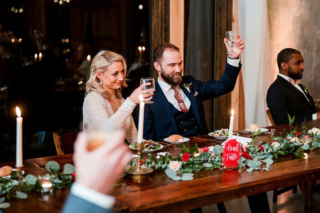 Bride And Groom Raising Their Glasses At Their Reception Dinner