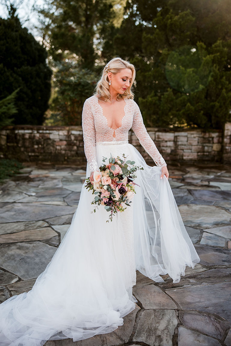 Bride Holding Dress And Posing With Bouquet