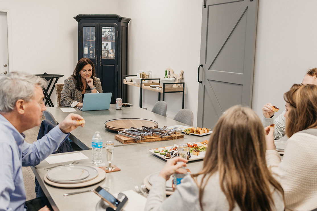 Staff member sits across from engaged couple as they taste possible menu options for their wedding