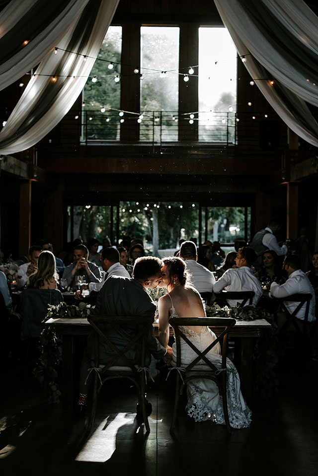 bride and groom kissing at head table at reception