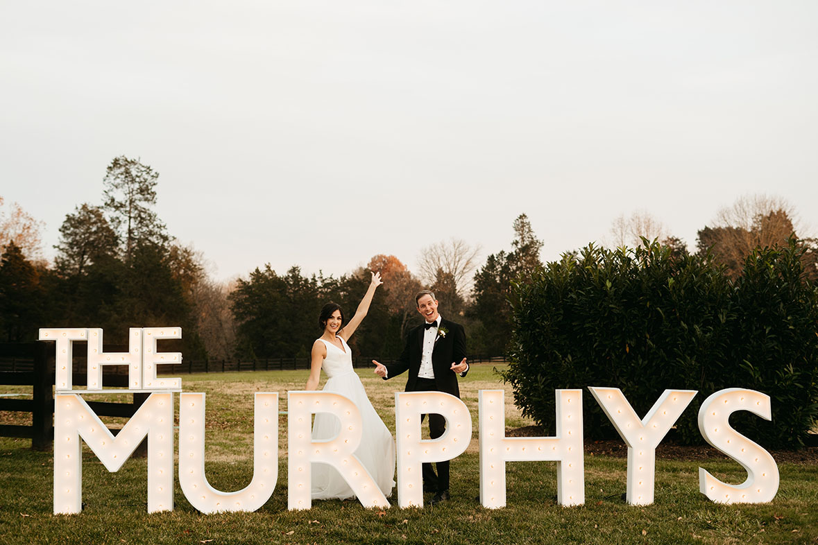 bride and groom with light up sign of their last name