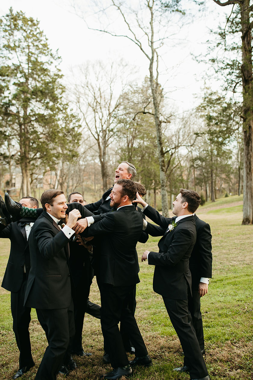 groomsmen crowdsurfing groom wearing classic black tuxedos