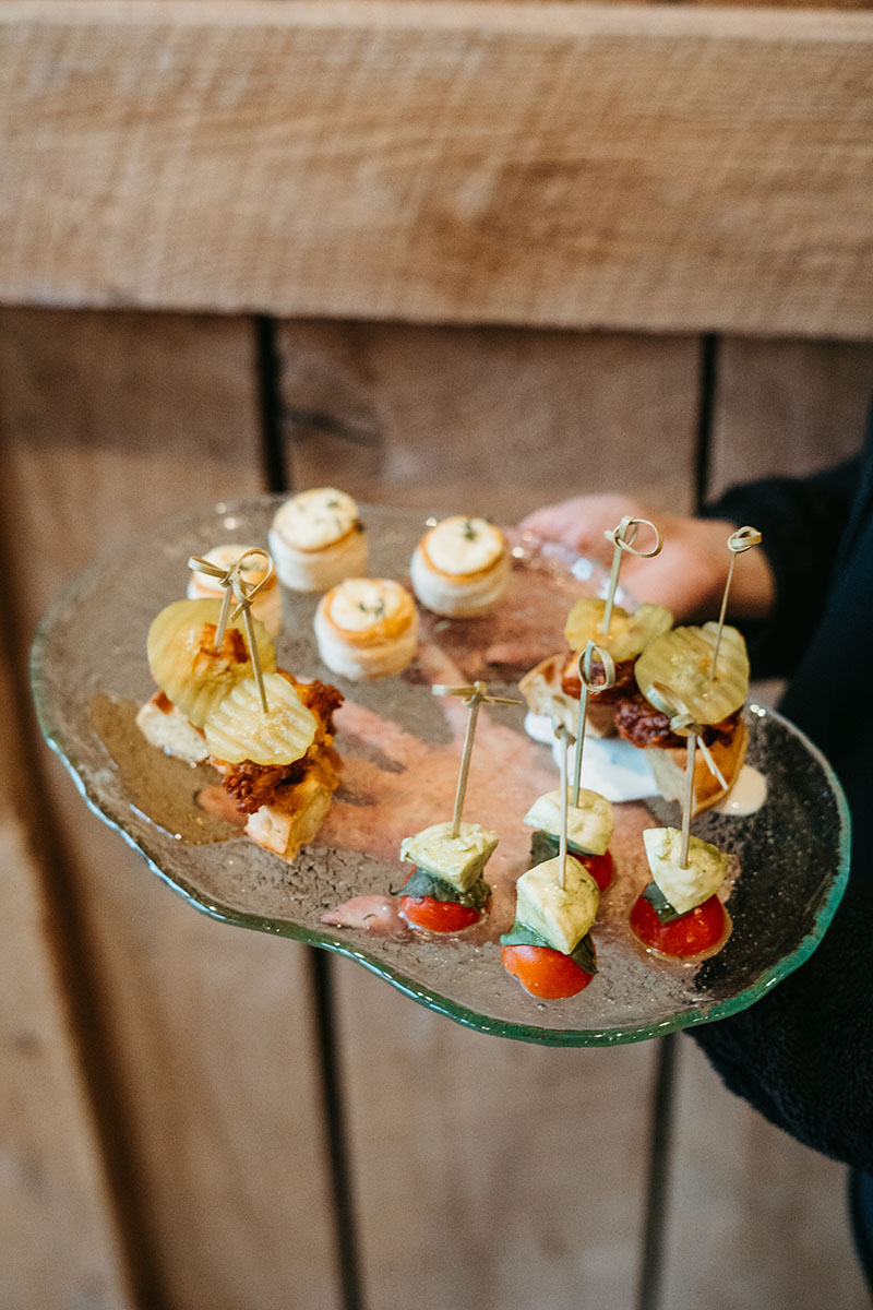 appetizer tray with cheese tarlets, chicken and waffles, and mini caprese skewers