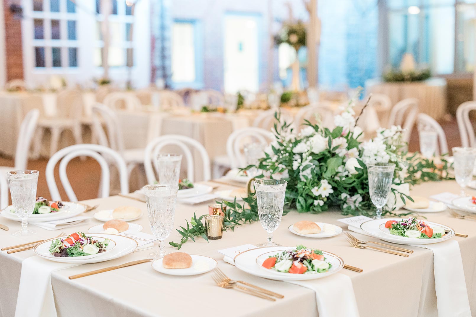 plated wedding salad at reception with greenery centerpieces and gold utensil accents