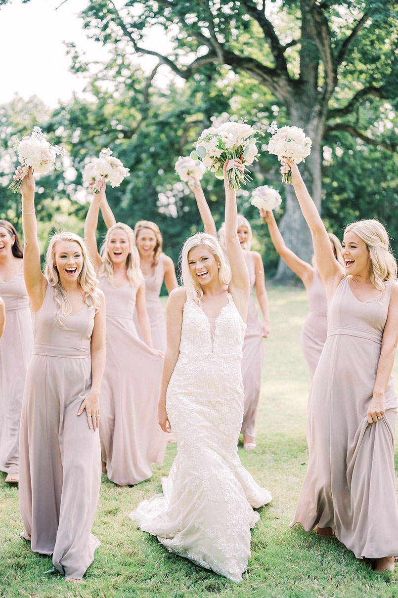 bride and bridemaids cheering with bouquets in the air