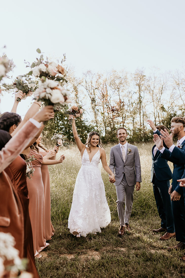 bride and groom walking through wedding party tunnel