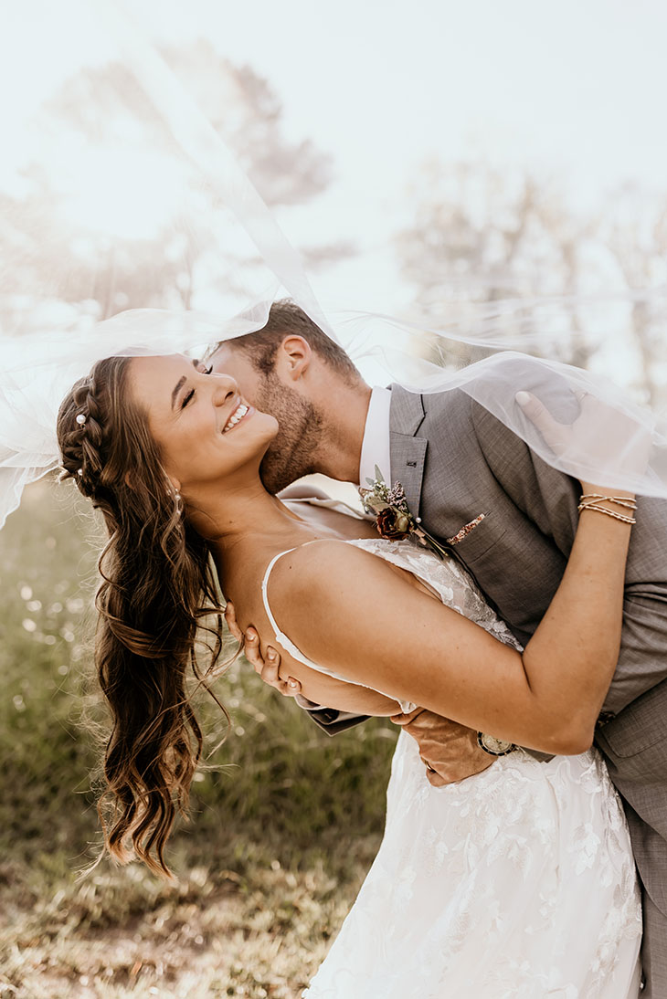 groom dipping bride at sunset