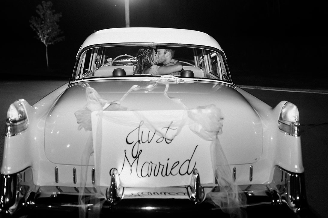 couple kissing in the back of just married getaway car