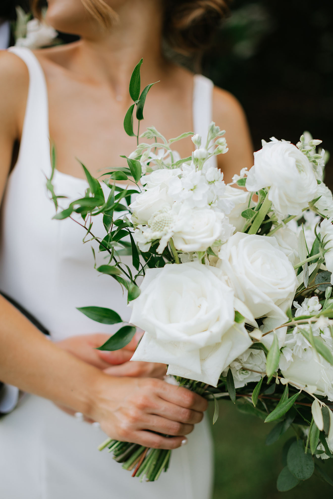 The bride's bouquet full of white roses, dainty white flowers, and leafy greenery