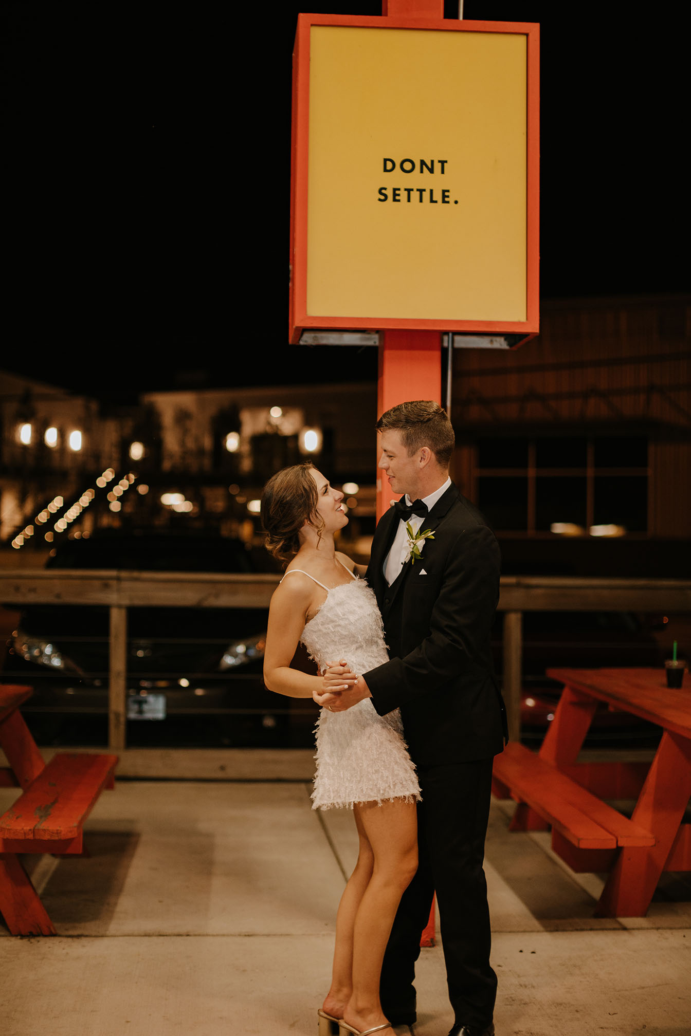 Newlyweds pose under a sign that says "Don't settle" at Daddy's Dogs restaurant in Nashville