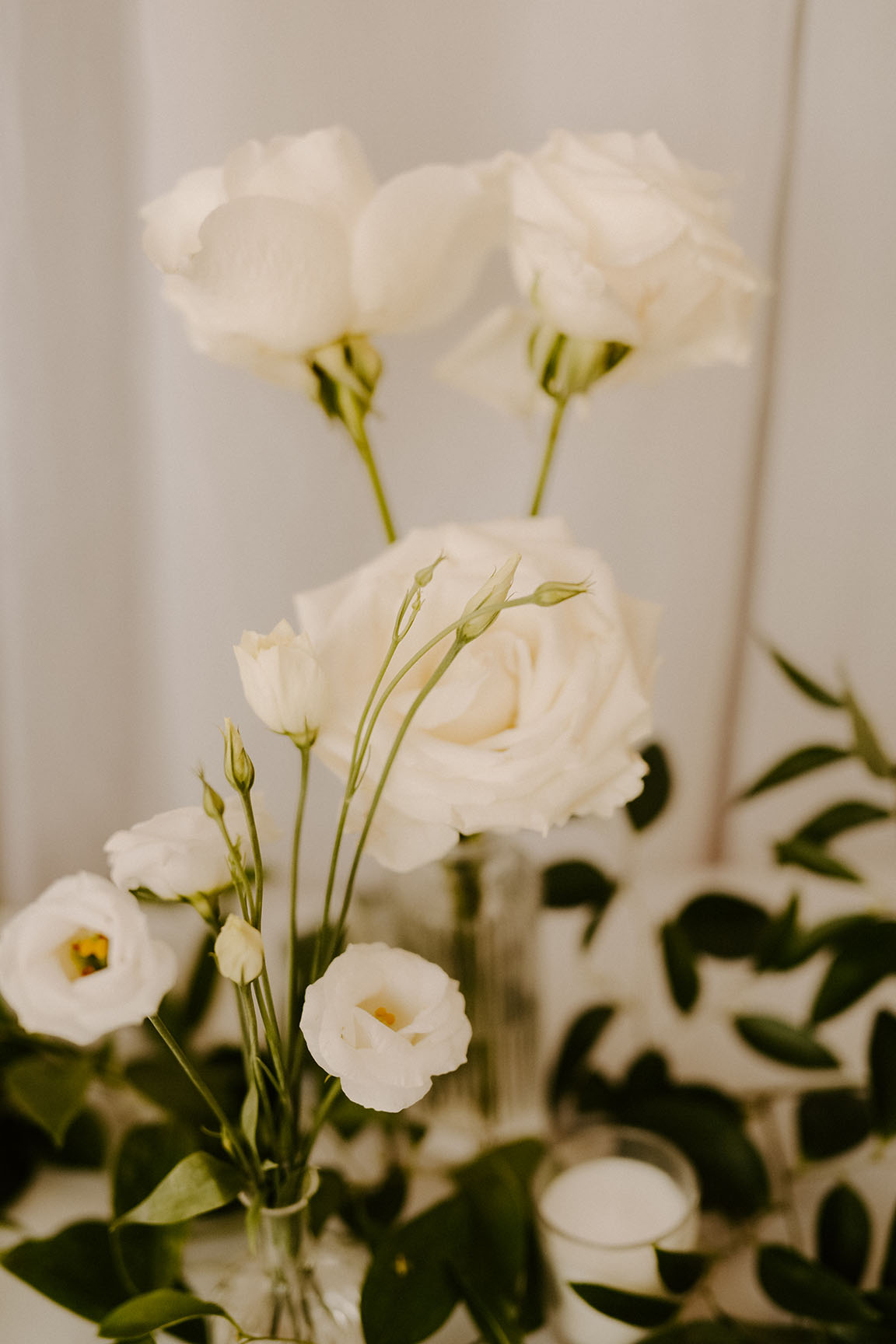 A close-up shot of a few white rose blooms in small bud vases