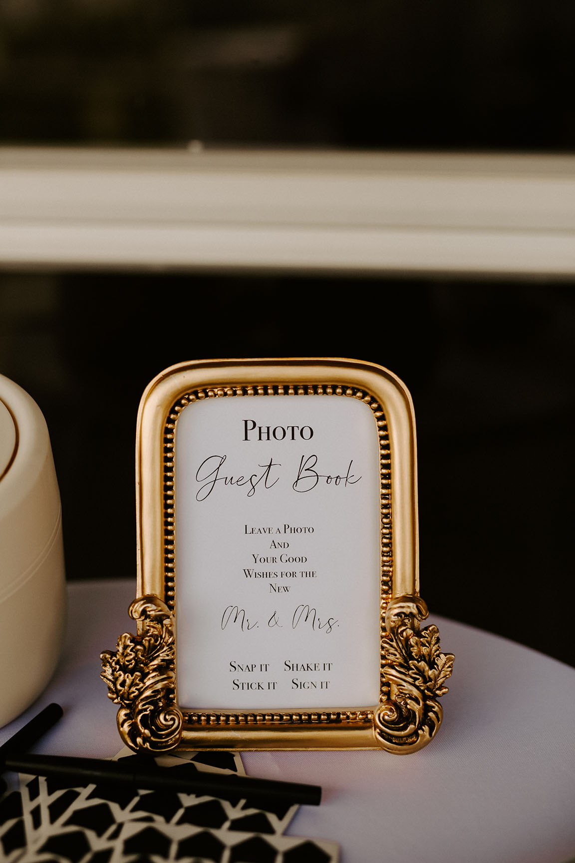 A small sign in an ornate gold frame telling guests how to use the photo guest book