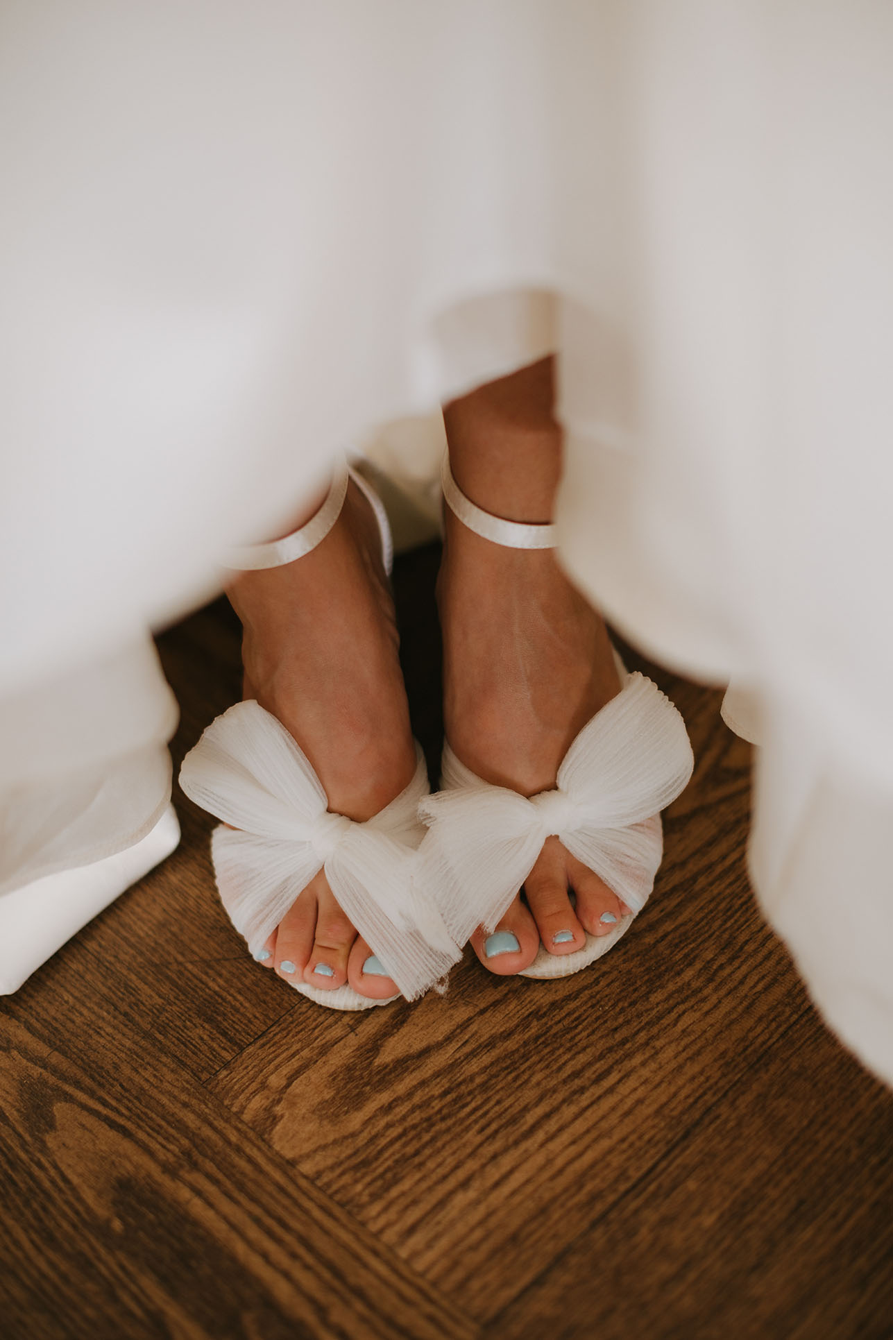 The bride's white wedding heels with an ankle strap and simple gauze bow