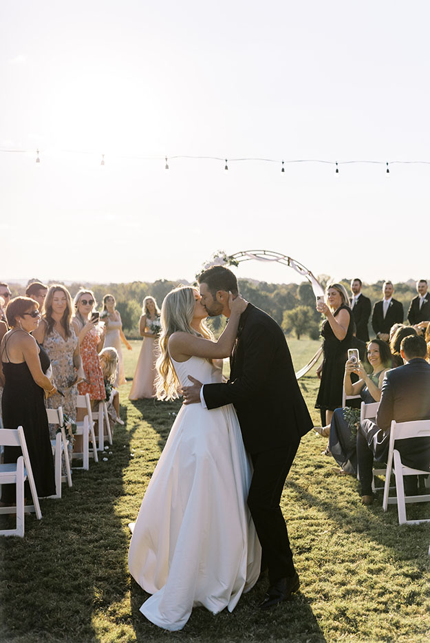 bride and groom kissing at wedding recessional