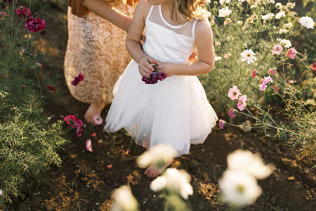 Close-up of flower girls without shoes in flower field at farm wedding venue