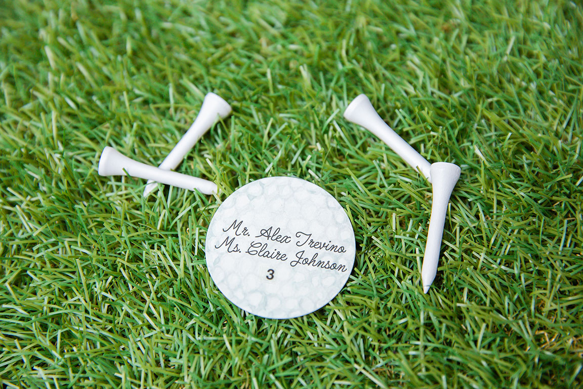 Close-up of escort card shaped like a golf ball and sitting on astroturf