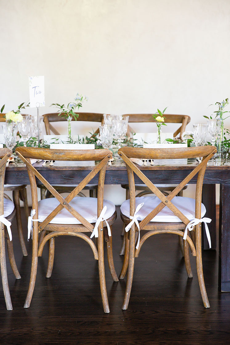 Side view of rehearsal dinner table with light wood crossback chairs