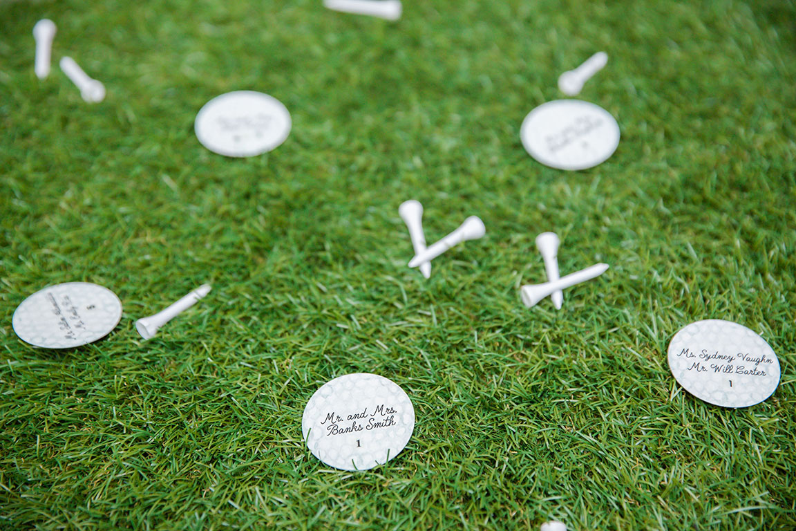 Golf-ball shaped escort cards laying on astro turf with golf tees