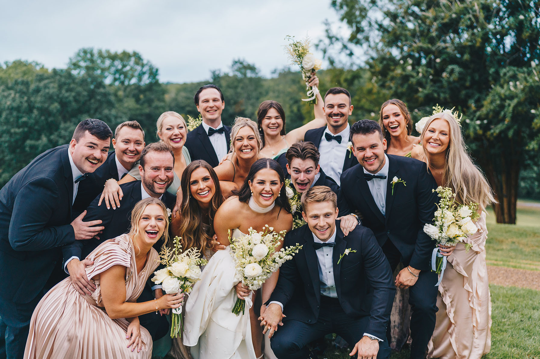 The bride and groom smile with their large wedding party