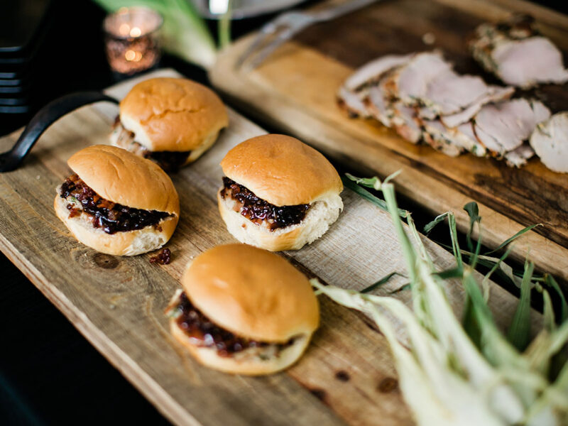 A close-up of slider burgers being served on a wooden board