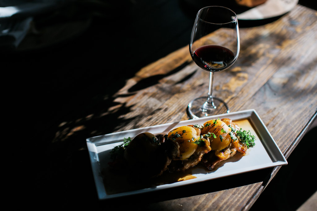 Peach chipotle chicken next to a glass of red wine